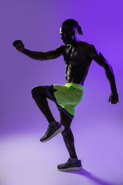 Black athlete doing high knee exercise with resistance band
