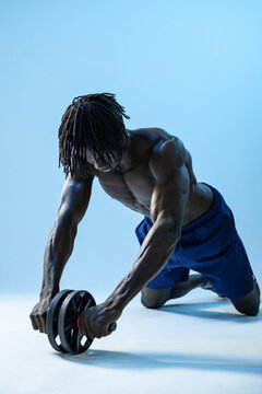 Black athlete doing ab wheel rollout in studio training