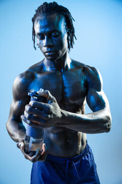 Focused black athlete holding shaker bottle in studio
