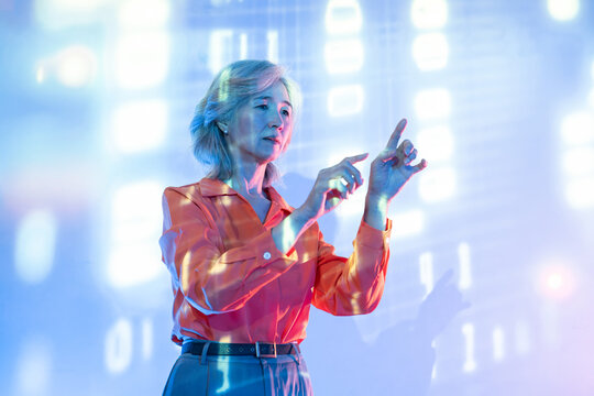 Futuristic senior Asian woman using hologram interface
