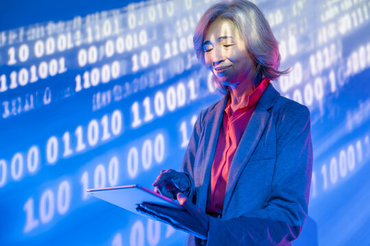 Futuristic senior Asian woman using tablet with data light