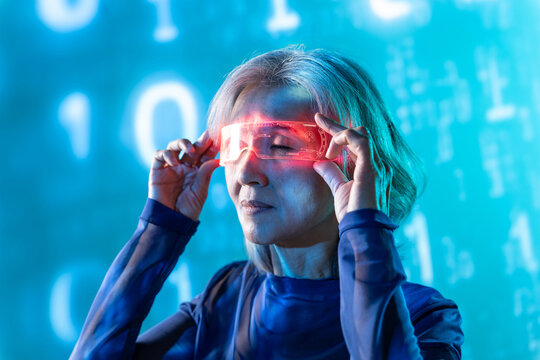 Futuristic senior Asian woman using AR glasses in neon