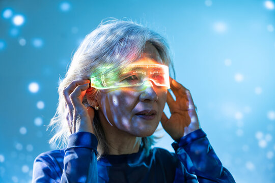 Futuristic senior Asian woman using glowing AR visor