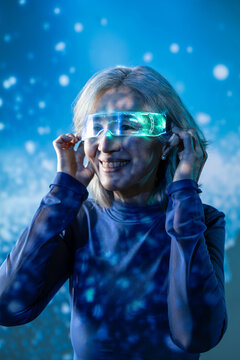 Futuristic senior Asian woman using glowing smart glasses