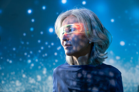 Futuristic senior Asian woman wearing AR visor in blue light