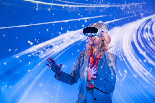 Senior Asian woman using VR headset in futuristic light