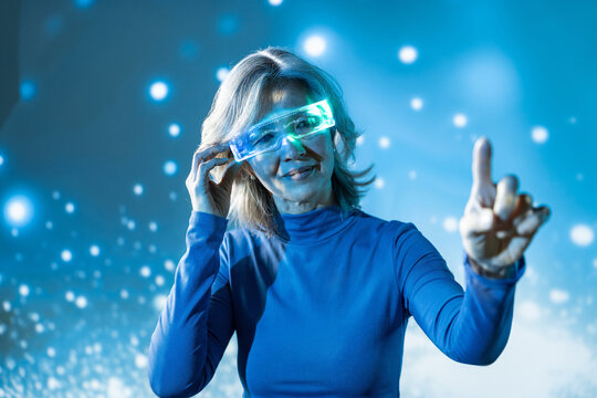 Futuristic senior Asian woman using glowing AR glasses