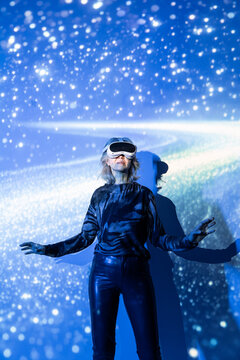Futuristic senior Asian woman wearing VR headset in blue light