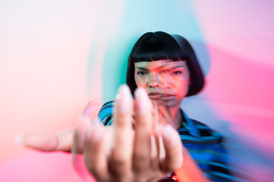 Young Latin woman reaching forward in neon blur portrait