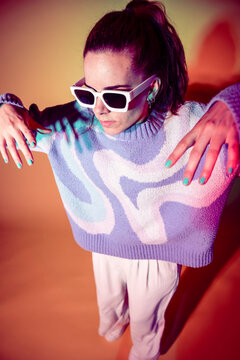Young woman dancer posing under colorful neon studio light