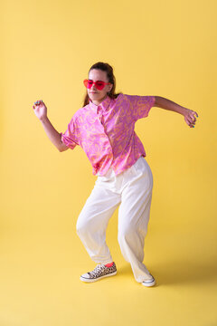 Young woman dancer in pink shirt on yellow studio backdrop
