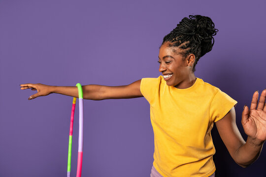 Fit afro woman playing with hula hoop in studio setting