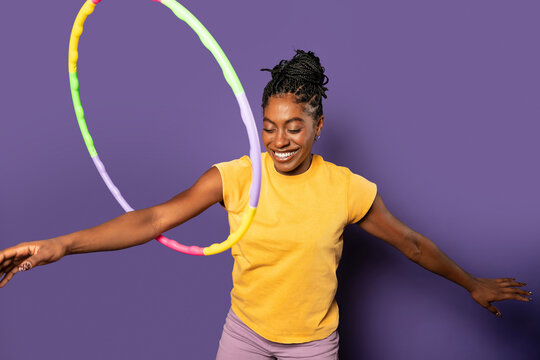 Fit Afro woman playing with hula hoop in studio