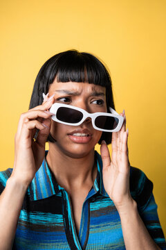 Latin young woman adjusting sunglasses with puzzled look