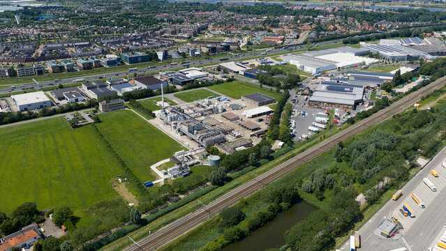 Aerial view of the Seqora B.V. industrial facility surrounded by green fields, railway tracks, and urban infrastructure in Zaltbommel, Gelderland, Netherlands.