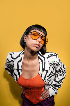 Stylish latin young woman posing in zebra jacket on yellow