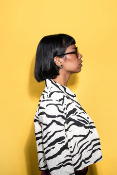 Latin young woman in zebra shirt profile on yellow backdrop