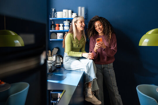 Multiethnic flatmates laughing together in modern kitchen