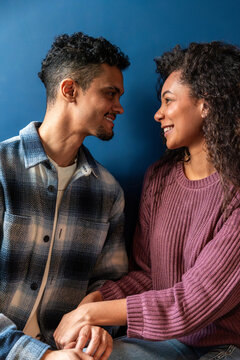 Latin couple smiling face to face holding hands indoors