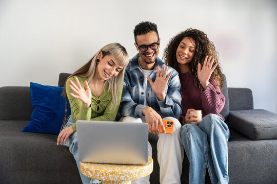 Multiethnic flatmates waving during laptop video call