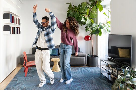 Latin couple dancing happily in bright modern living room