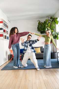 Multiethnic flatmates dancing limbo in modern living room