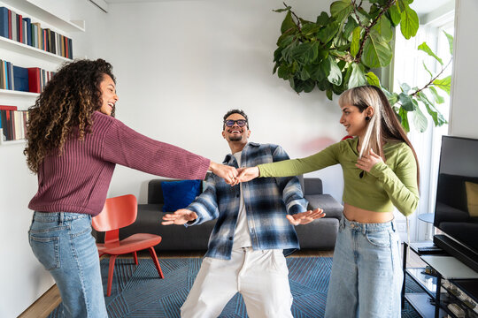 Multiethnic flatmates dancing limbo game in living room