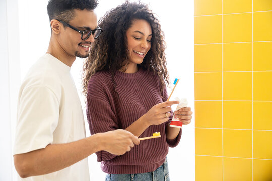 Latin couple brushing teeth together in bright bathroom