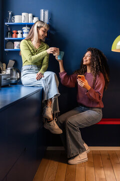 Multiethnic flatmates sharing coffee in cozy kitchen