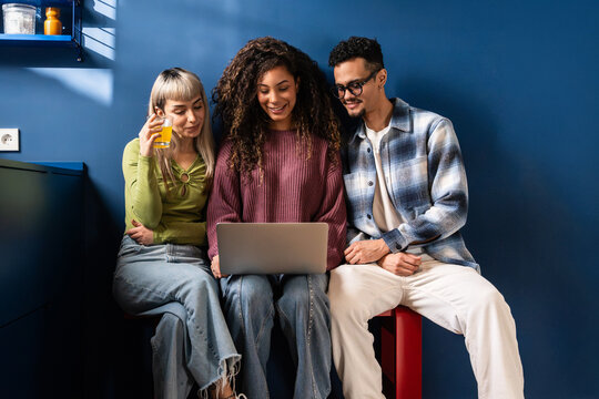 Multiethnic flatmates using laptop at home, relaxed
