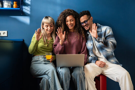 Multiethnic flatmates waving during video call at home