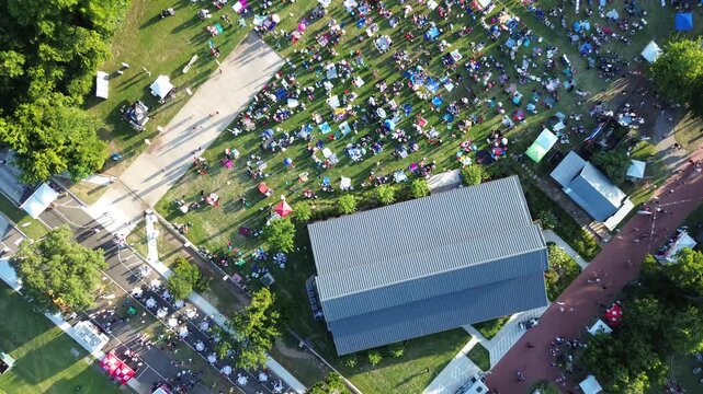 July Fourth Independence Day crowds assemble on lawn sections near Farmers Branch Historical Park structures. Soft sunlight illuminates vibrant outdoor community event in Dallas Fort Worth, TX