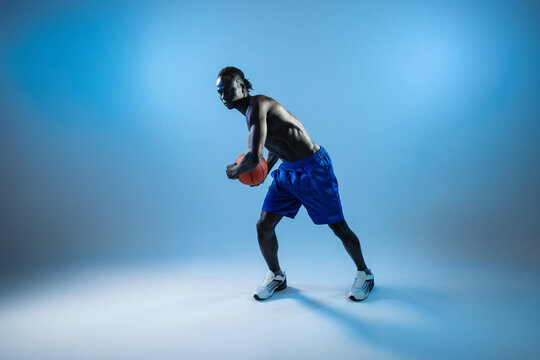 Black basket man holding basketball in blue studio light
