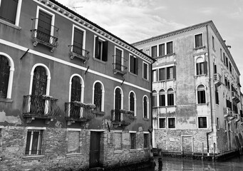 Naklejka premium Historic Venetian palaces along a quiet canal, black and white, Venice