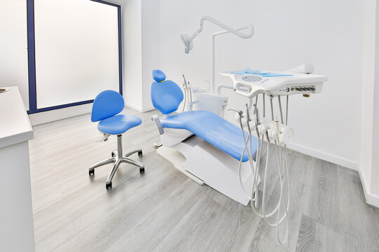 Bright dental clinic room with blue chair and equipment
