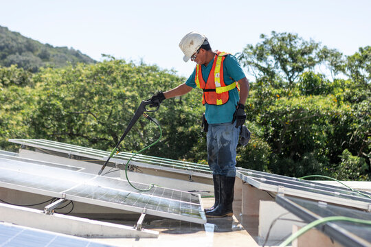 Solar panel maintenance by a worker on a sunny day