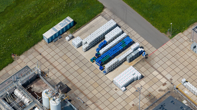 Aerial view of Seqora B.V. industrial site featuring rows of white and blue storage containers and drums on a concrete yard in Zaltbommel, Gelderland, Netherlands.