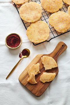 Dutch waffle cookies on rack with crumbs and spice bowl