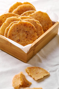 Dutch waffle cookies stacked in wooden tray on white cloth