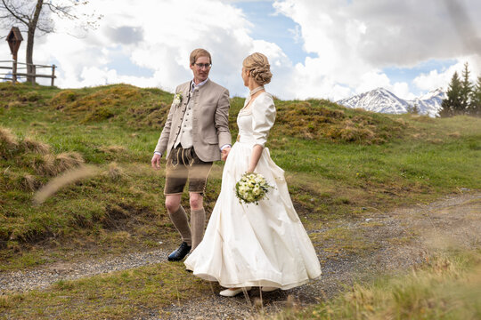 Wedding couple walking in Austrian alpine meadow landscape