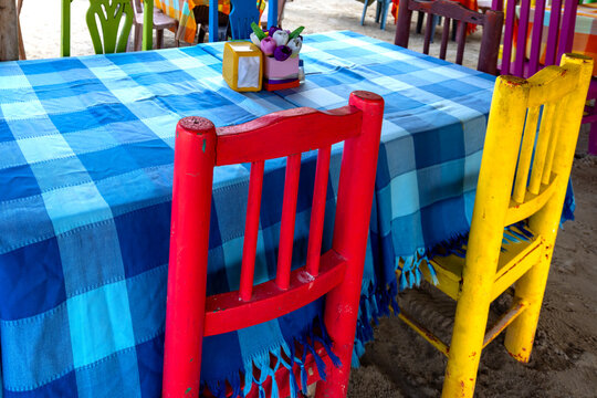 Colorful rustic chairs beside a blue checkered table