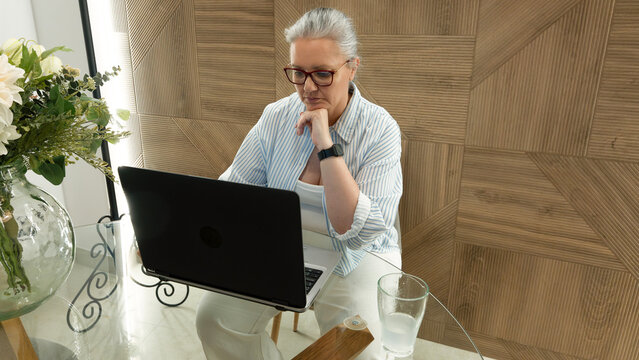 Senior woman working remotely on laptop at home office