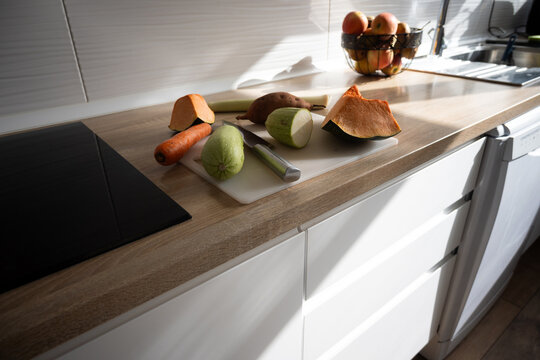 Sunlit kitchen counter with fresh vegetables on board