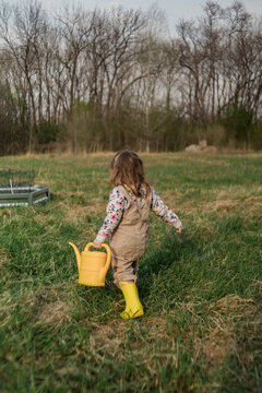 Little girl exploring a garden with a watering can