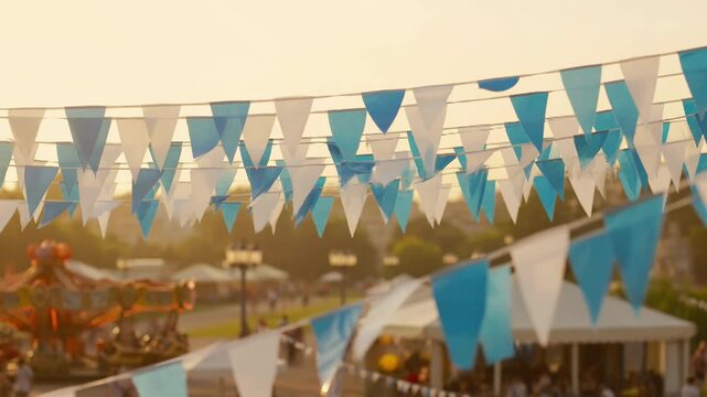 Festive bunting flags flutter above a lively amusement park with a carousel