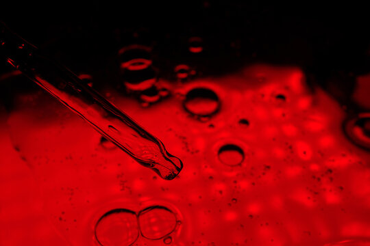 Abstract red liquid macro with bubbles and pipette dropper