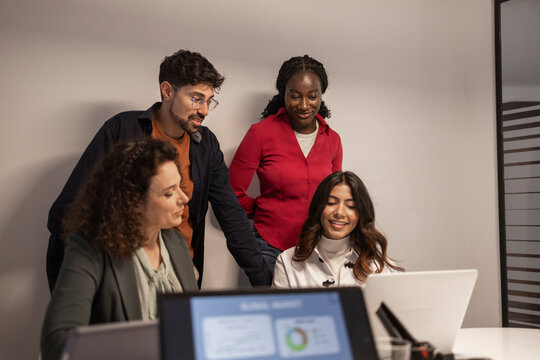 Diverse team brainstorming around laptop in coworking office