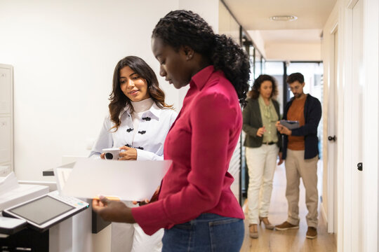 Coworking team reviewing documents in modern office corridor