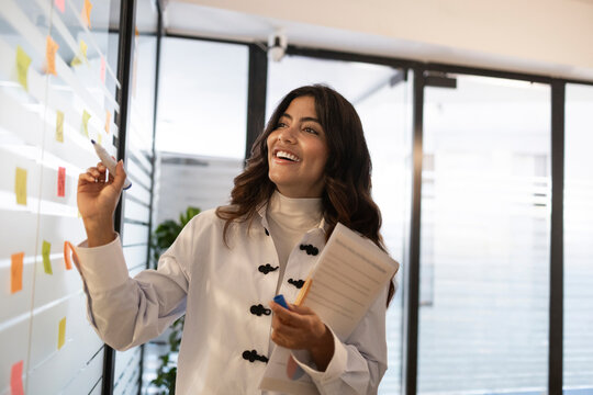 Woman brainstorming with sticky notes in coworking office