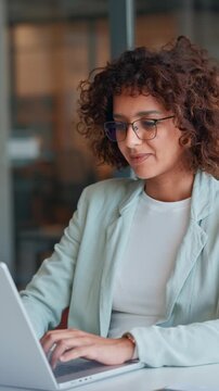 Indian or muslim arabian businesswoman working on laptop at office desk. Professional woman ceo entrepreneur using pc computer for online finance management or marketing sitting at workplace. Vertical